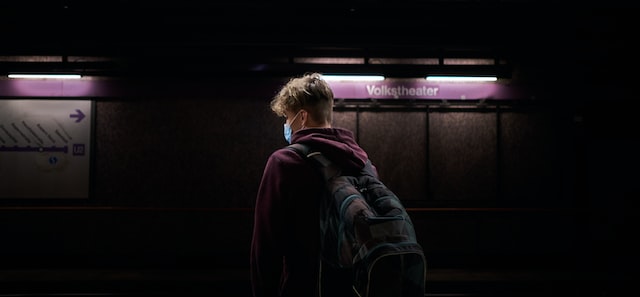 Junge Person steht am Gleis einer U-Bahn