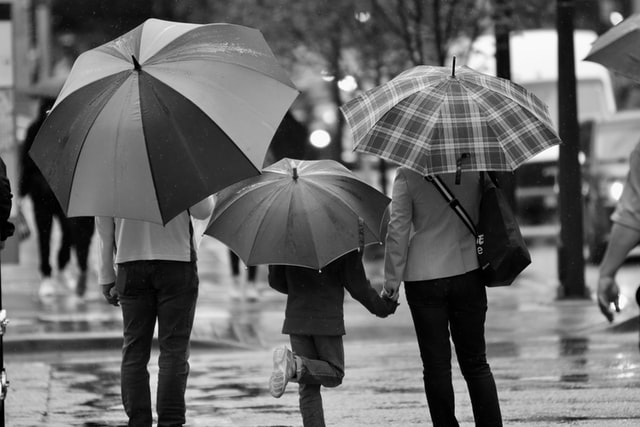 Drei Personen unter Regenschirmen