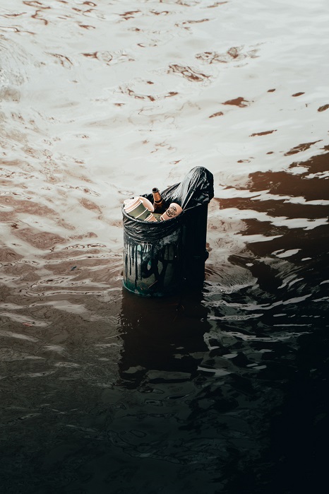 Allein stehender randvoller Mülleimer in hoch stehenden Wassermassen