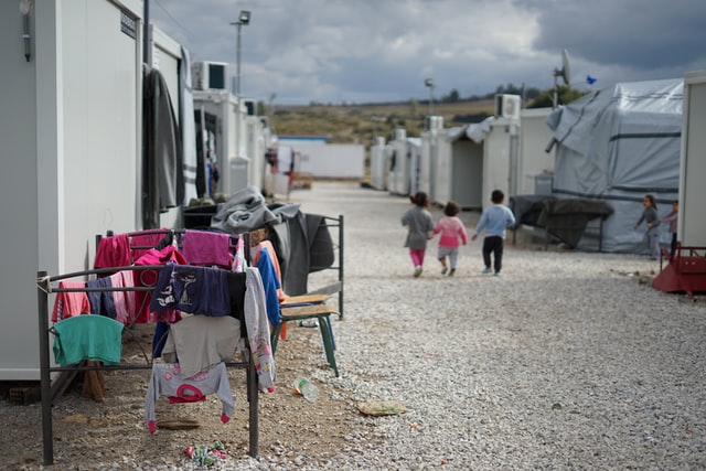 Drei Kleinkinder laufen zwischen Zelten durch ein syrisches Flüchtlingscamp nahe Athen