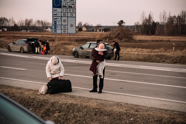 Ukrainische Flüchtende mit Reisegepäck am Straßenrand bei der Grenze