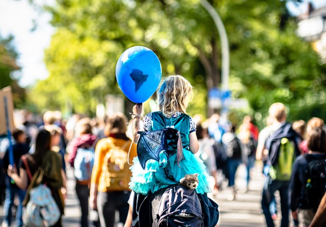 Kind mit blauem Luftballon auf den Schultern einer erwachsenen Person