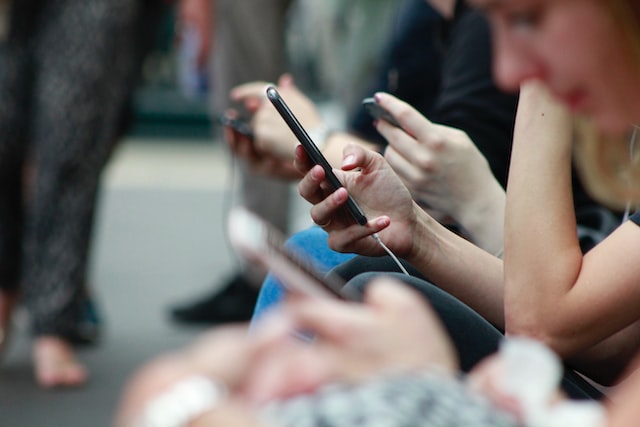 Mehrere Personen sitzen mit ihrem Smarthone in der Hand