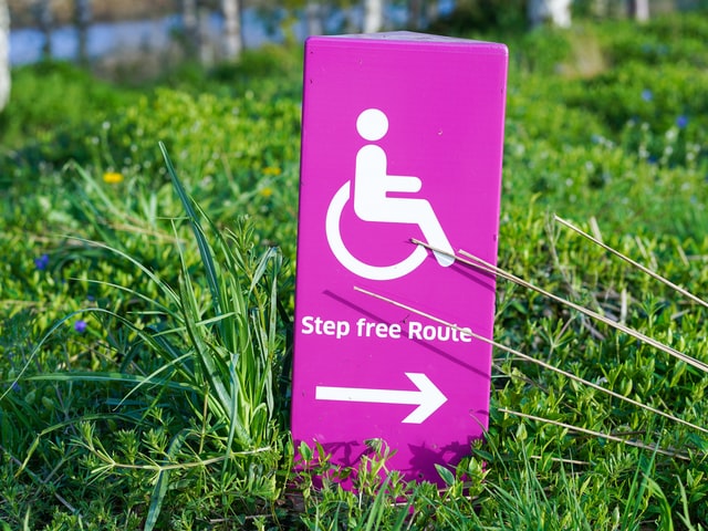Schild mit Rollstuhl Symbol und einer Richtungsweisung: 