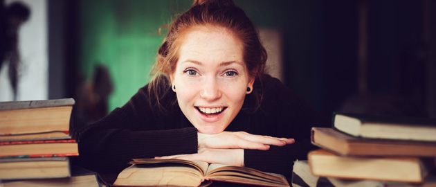 Lachende junge Frau über ihren Büchern 